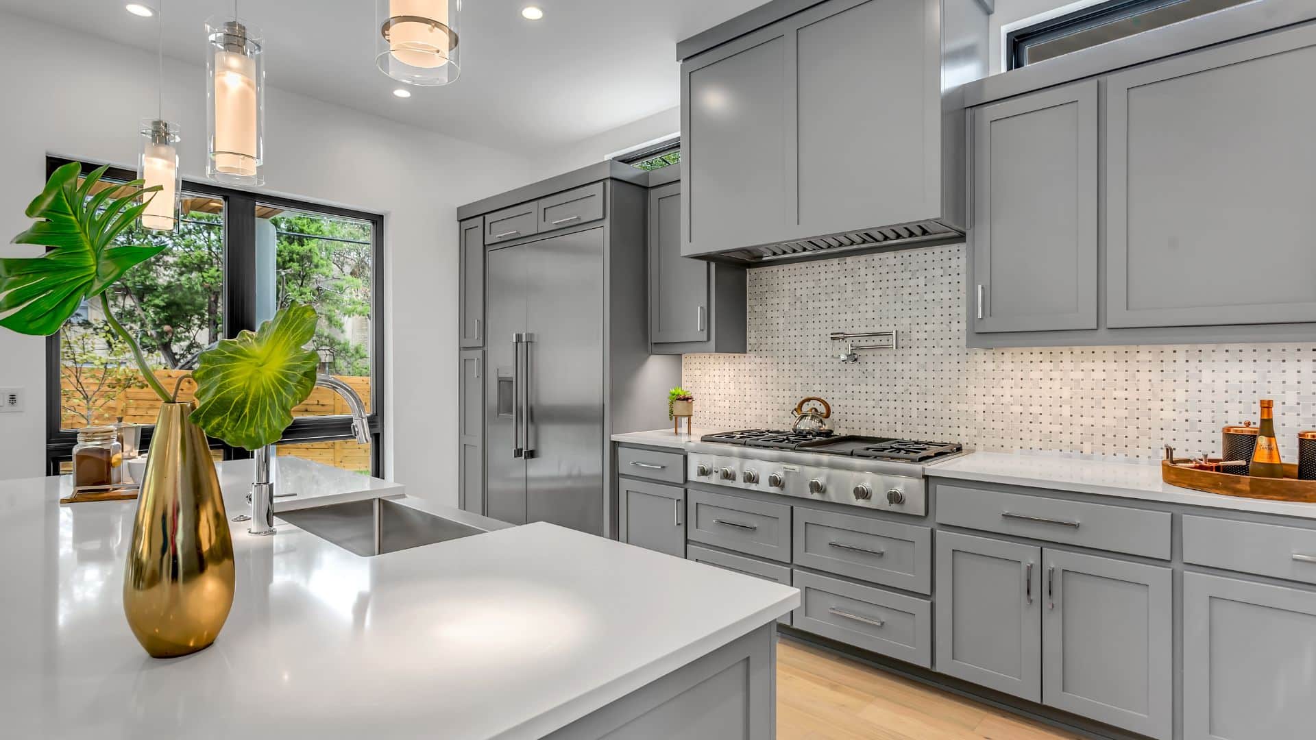 Grey kitchen cabinets with white countertop and backsplash