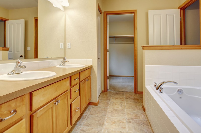 Traditional Bathroom style with classic oak cabinets with cream countertop and white bath tub