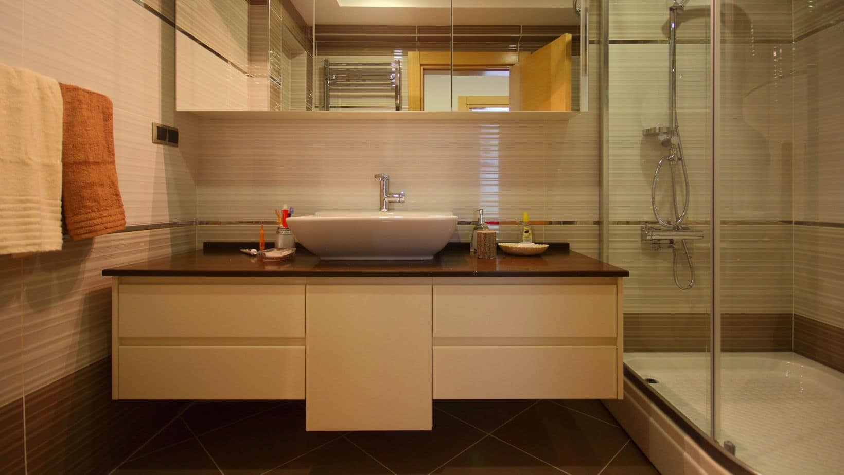 Cream modern bathroom with walk-in shower and flat brown cabinets