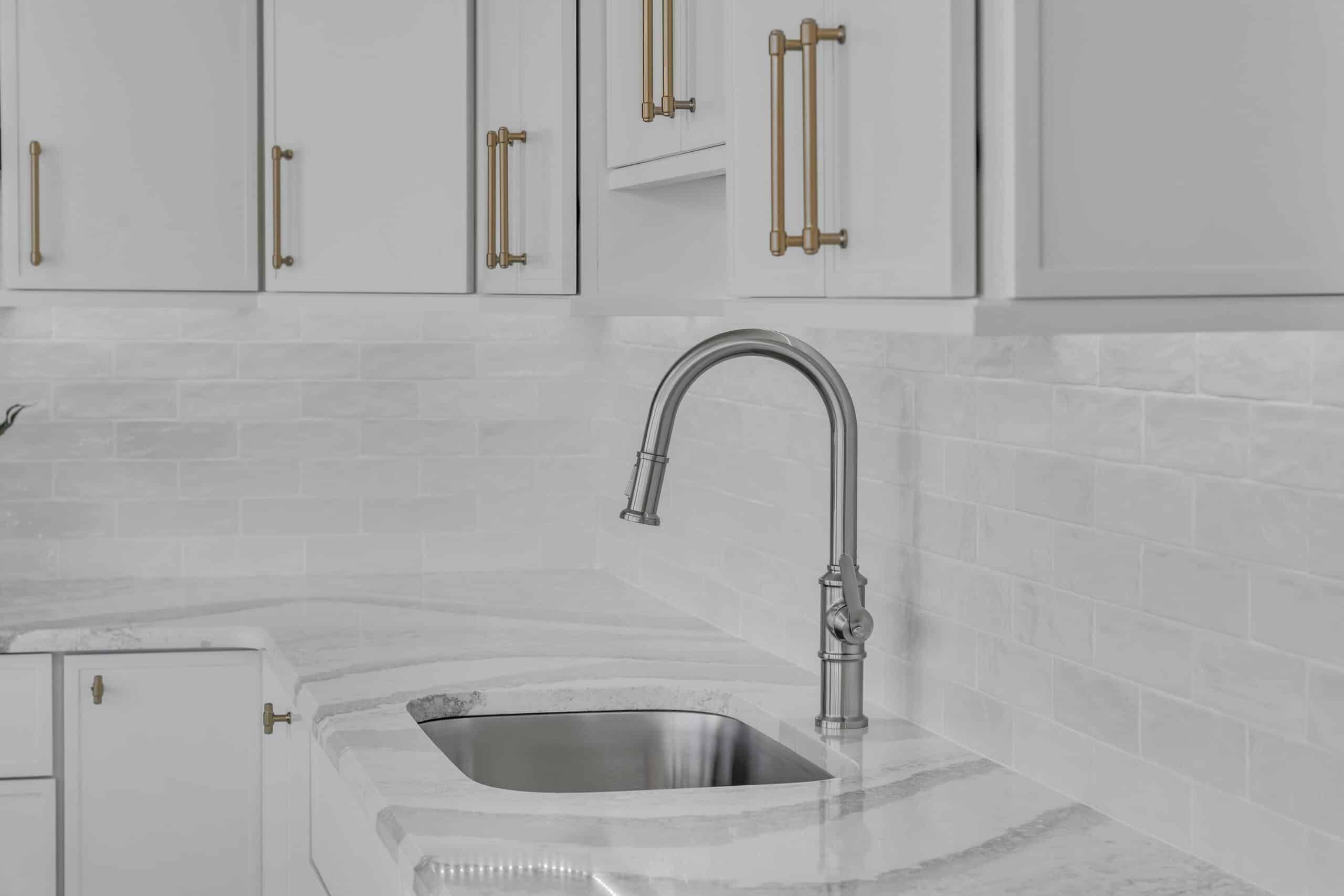 side view of kitchen sink and faucet with white wall cabinets
