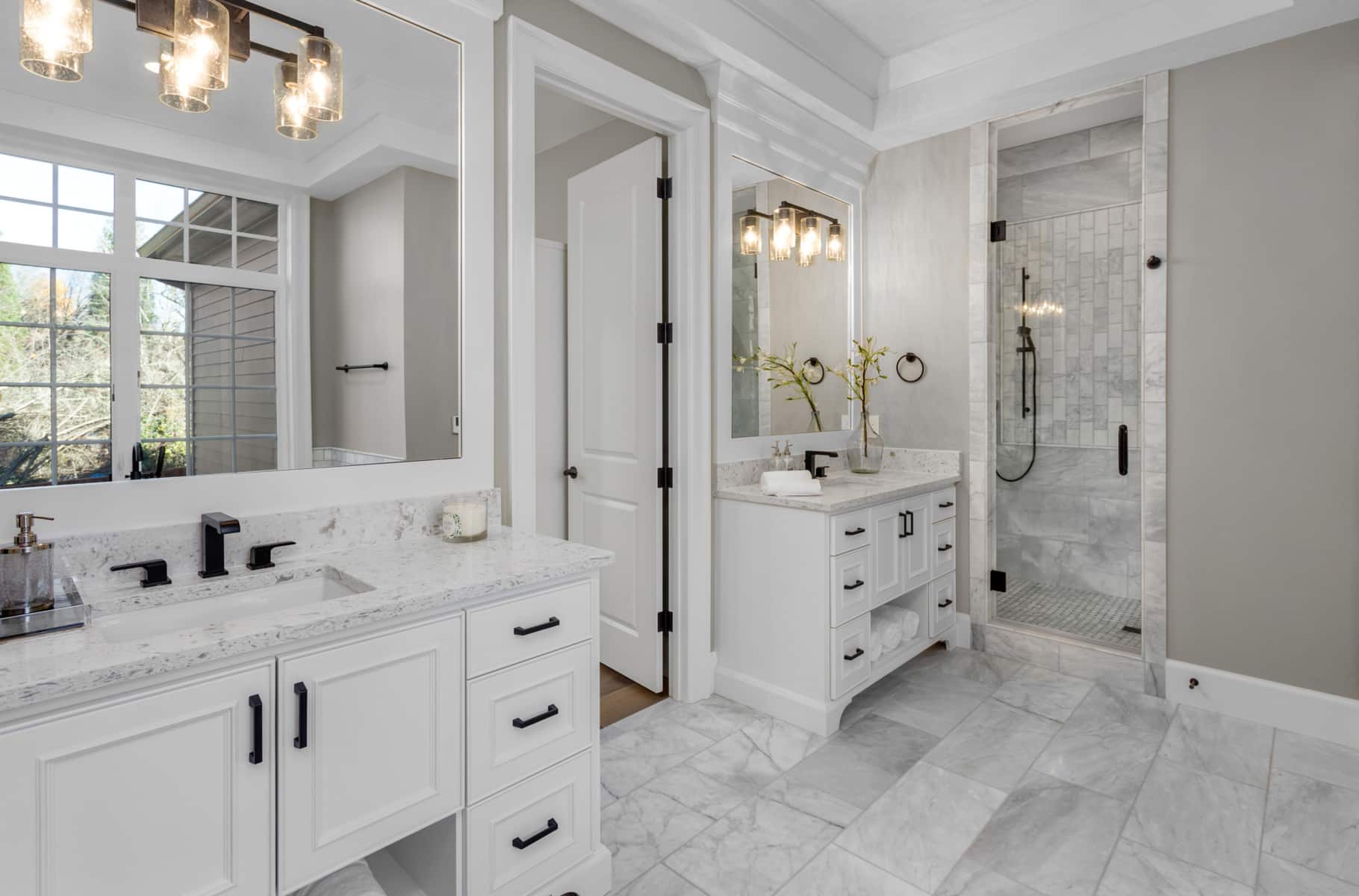 White bathroom with 2 single sink custom bathroom vanities, beside shower
