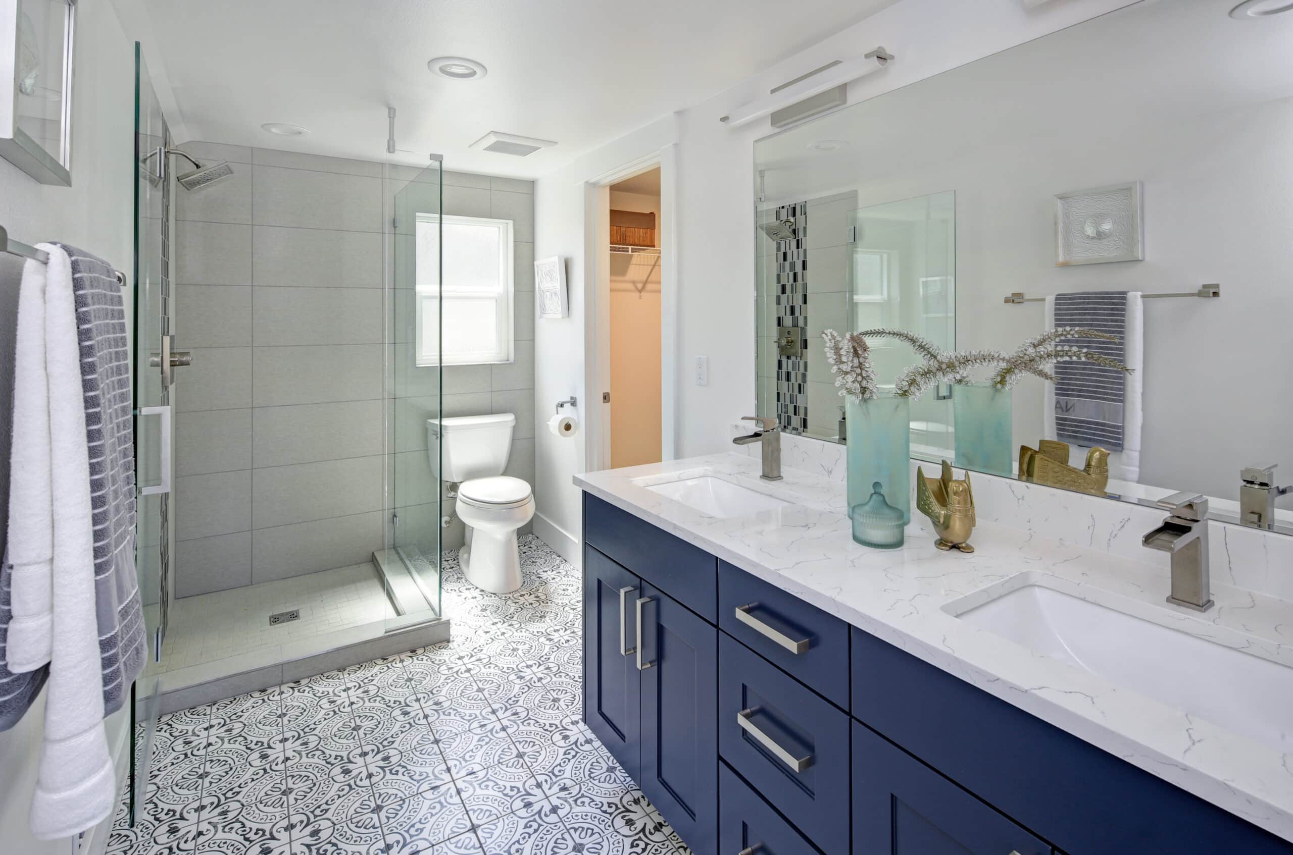 Modern bathroom interior with blue double vanity and glass shower.