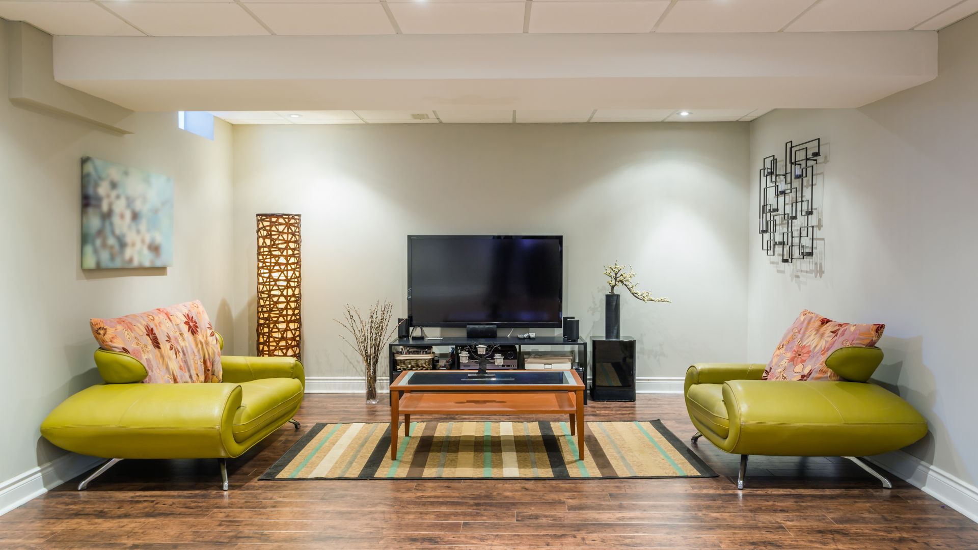 Living room in basement with widescreen television, green sofa and wood flooring