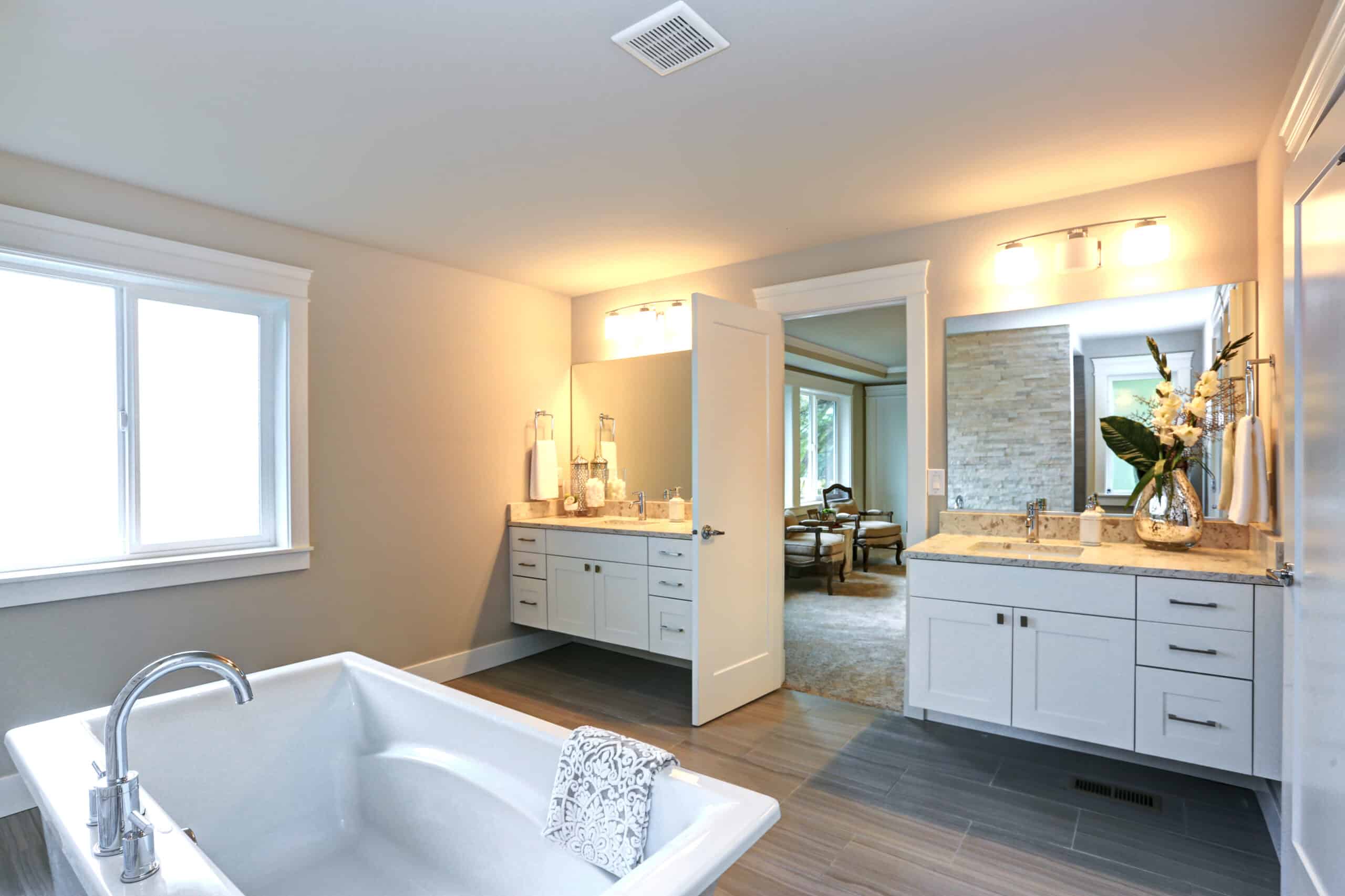 Amazing master bathroom with white bathroom vanities , marble countertops, rectangular mirrors and freestanding bathtub over Porcelain tiled floor.
