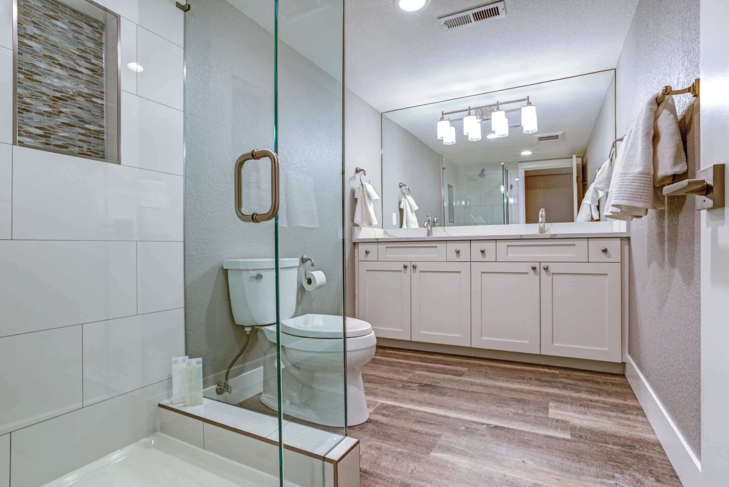 Elegant master bathroom with double vanity cabinet over hardwood floor.