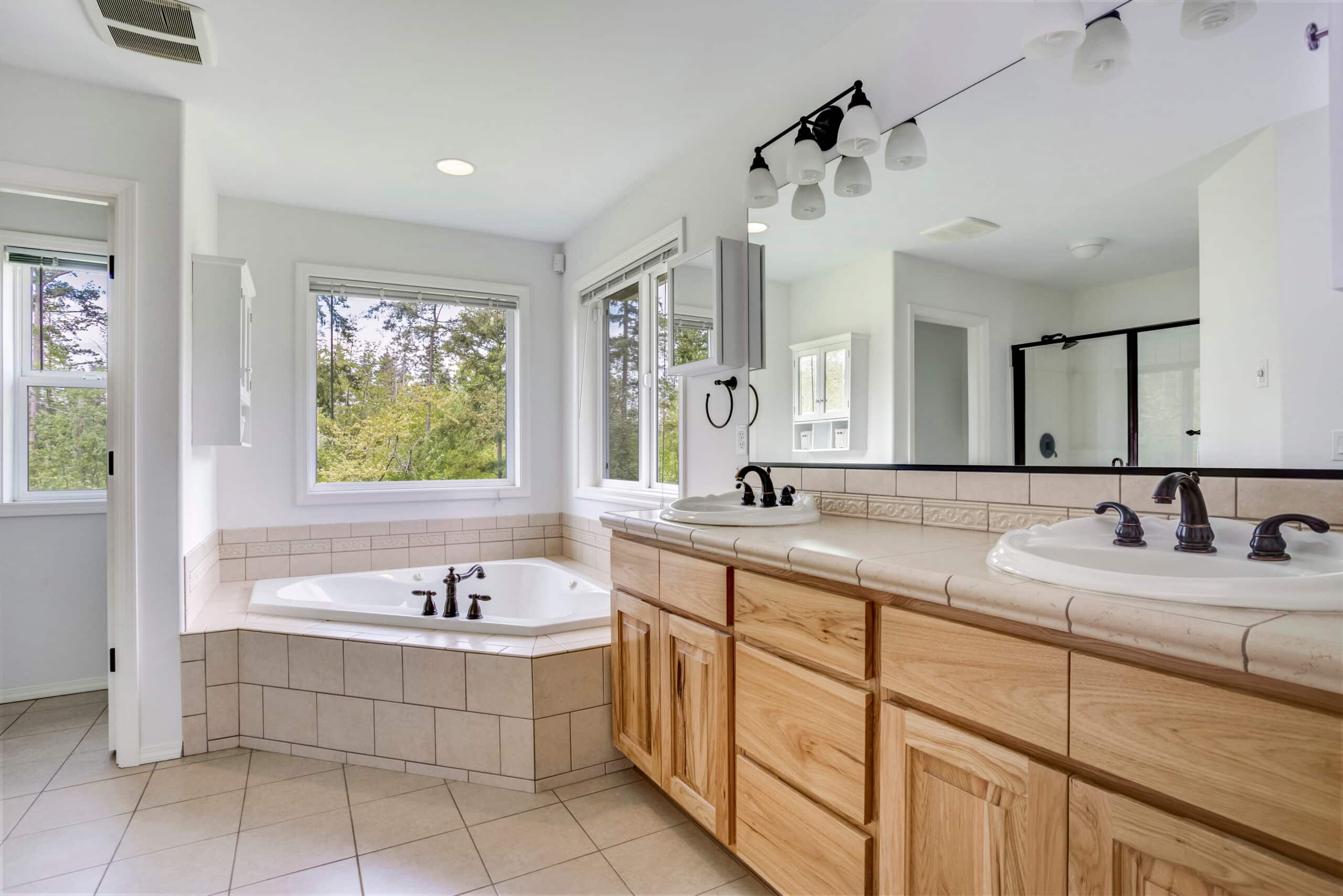 Traditional style bathroom with double sink wooden vanity, tiles, and a bath tub