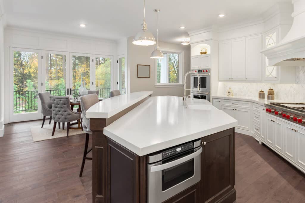 Beautiful kitchen in new luxury home with hardwood floors, white cabinets, and quartz countertops.