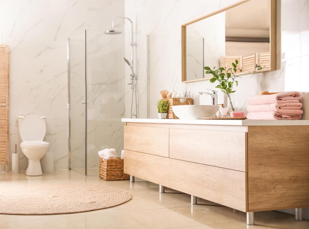 Clean white and light brown bathroom with free-standing contemporary vanity with vessel sink, an enclosed corner shower, and a toilet