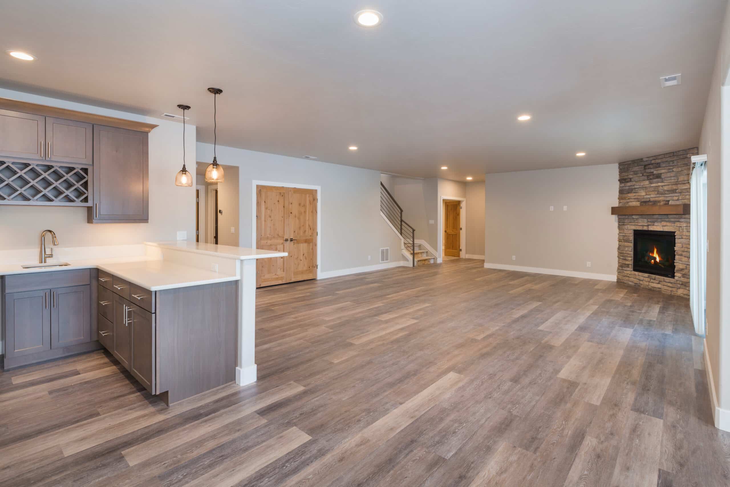 Spacious basement with fireplace, open kitchen in wooden flooring and light grey walls
