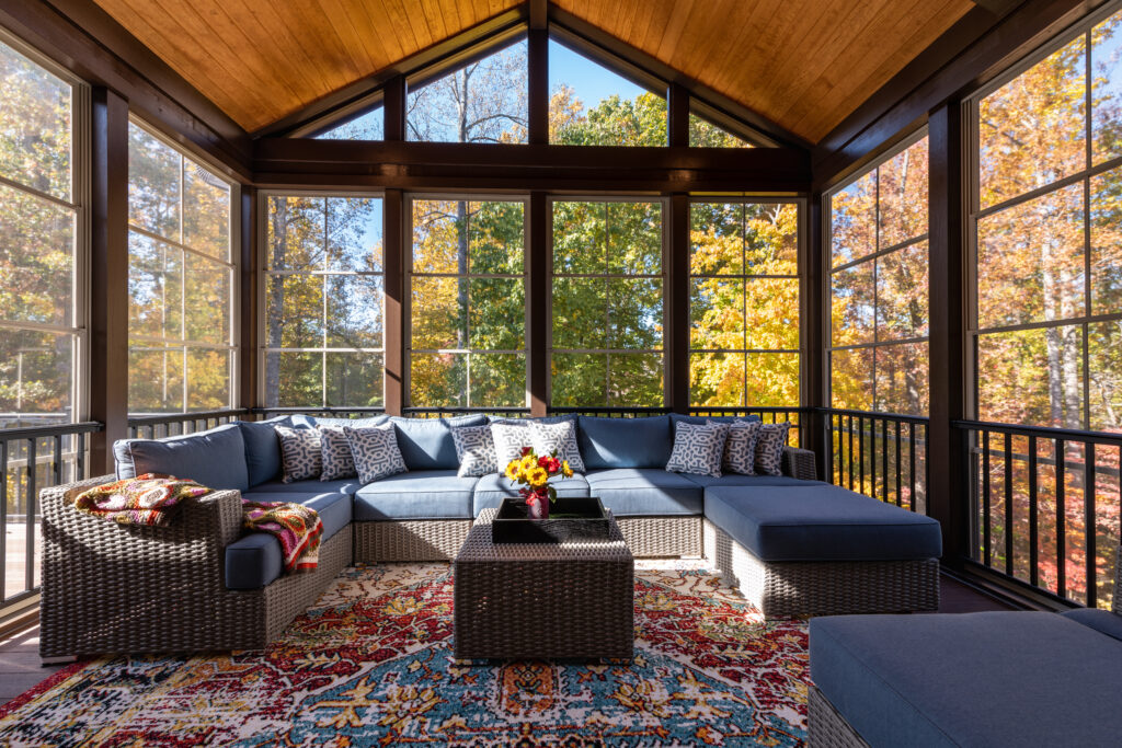 New modern living room screened porch with patio furniture, summertime woods in the background.
