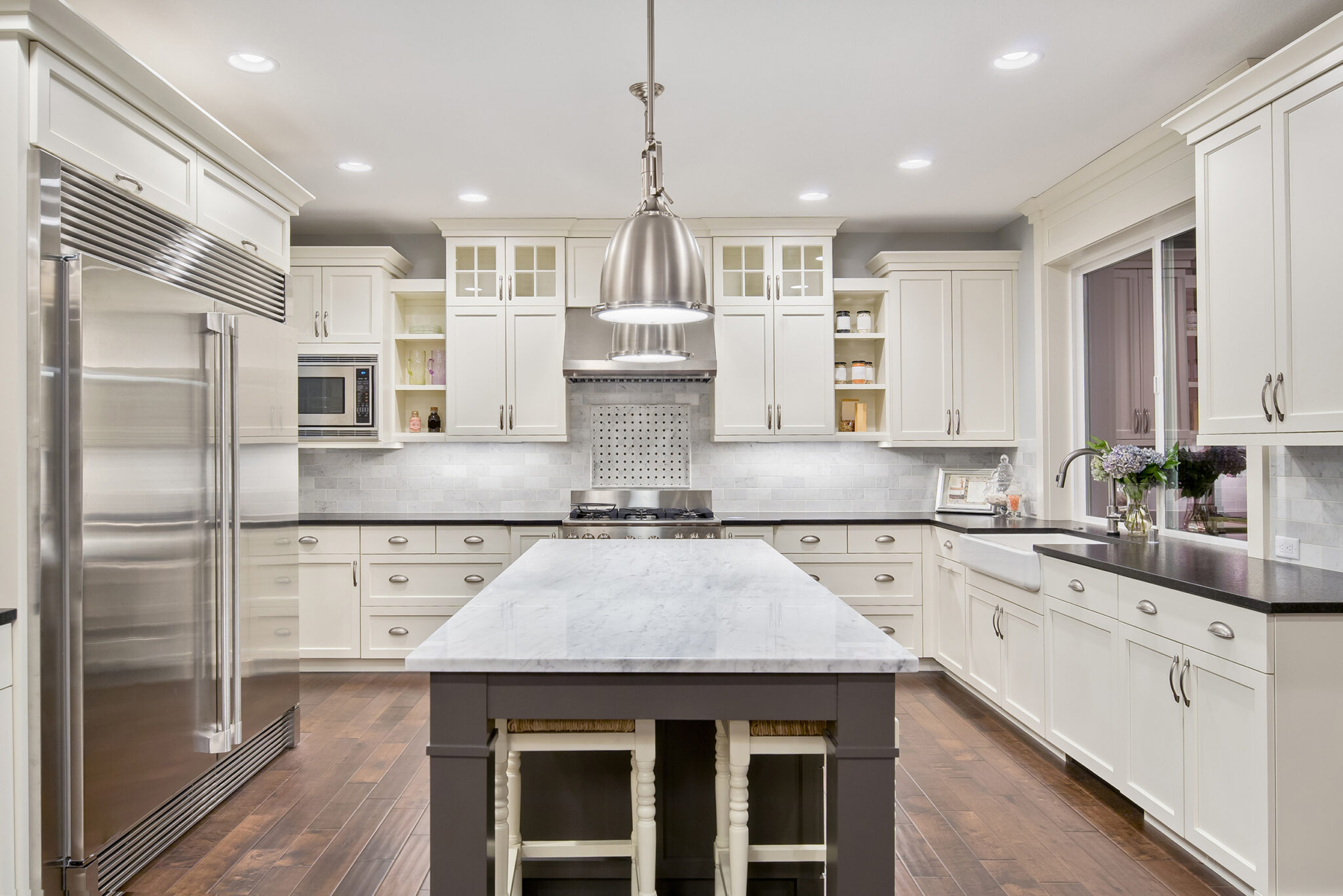 Light Spacious kitchen style with cream shaker cabinets, black countertops and centered kitchen island with white countertop