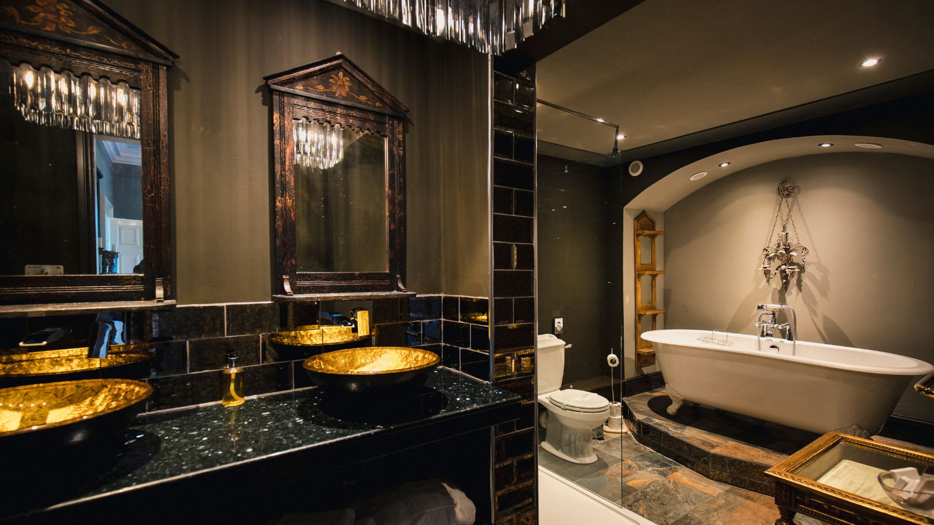 Rustic dark bathroom style with black countertop, and golden vessel sink