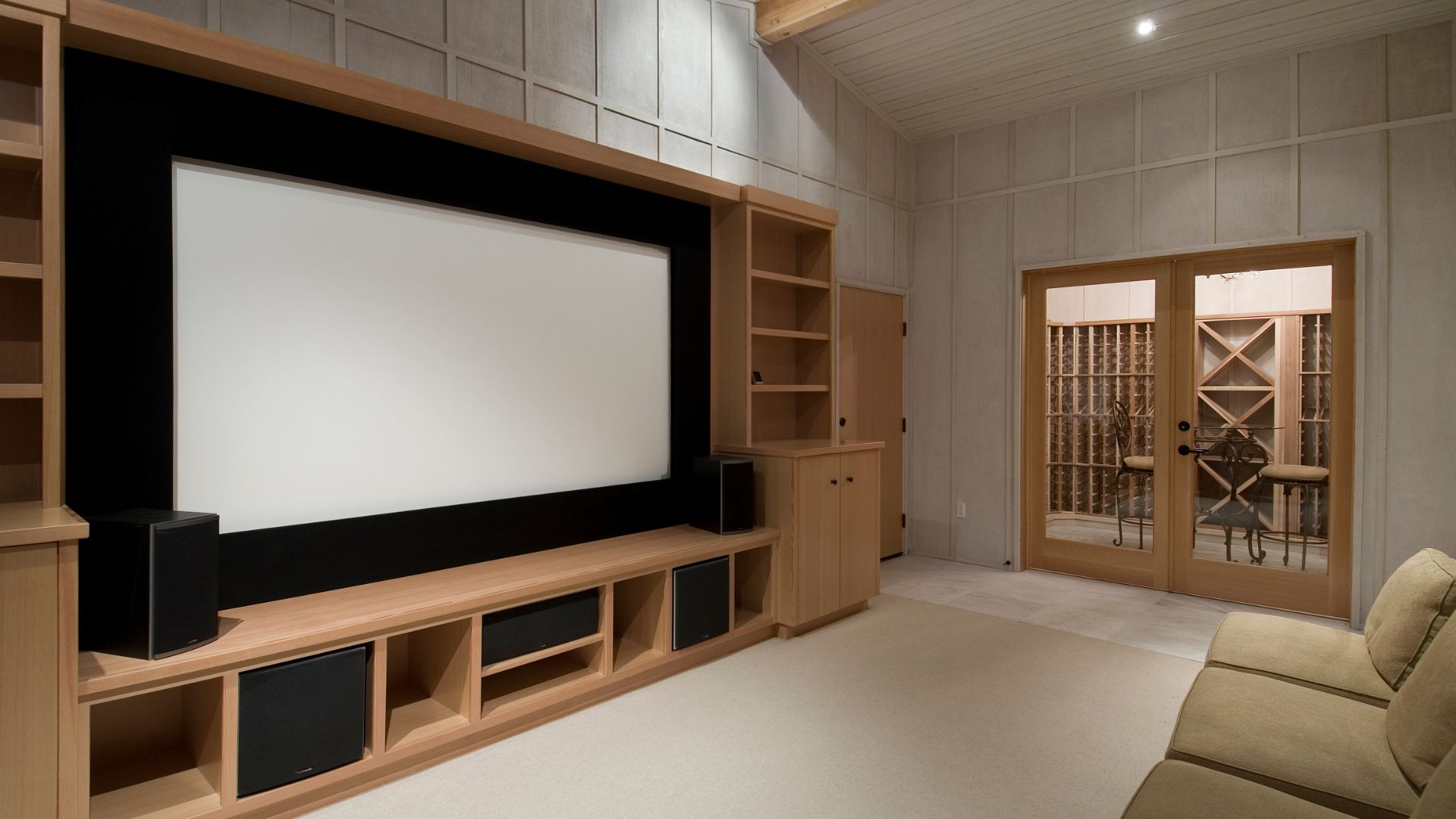 Basement Theatre with big cinematic TV enclosed by brown cabinet and cinema style chairs