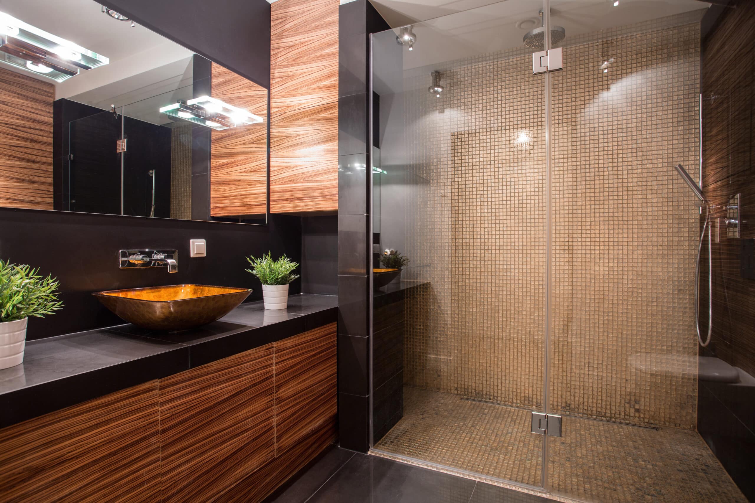Small dark bathroom with waterfall shower and dark brown vanity with black countertop