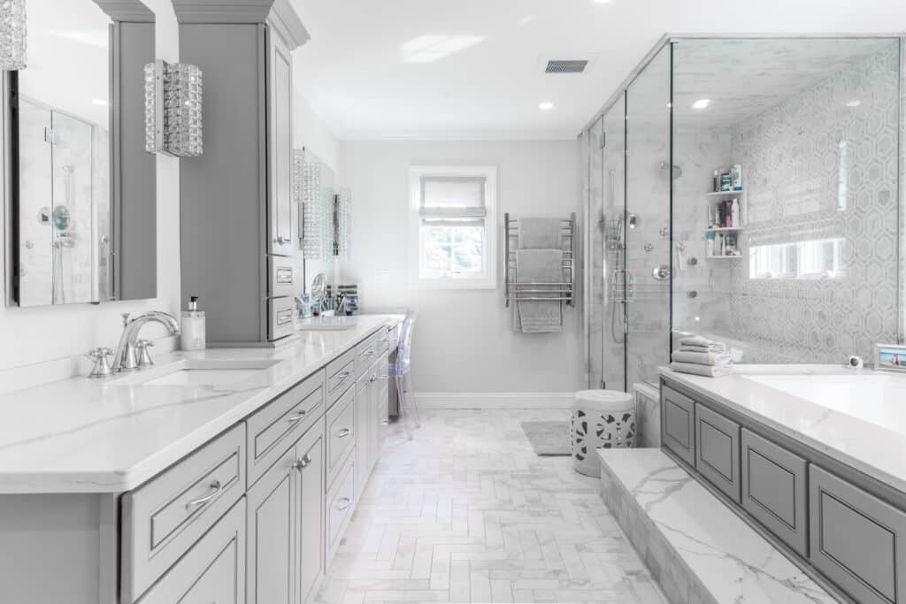 Grey bathroom with large walk-in shower and bath tub, and grey cabinets with white countertop