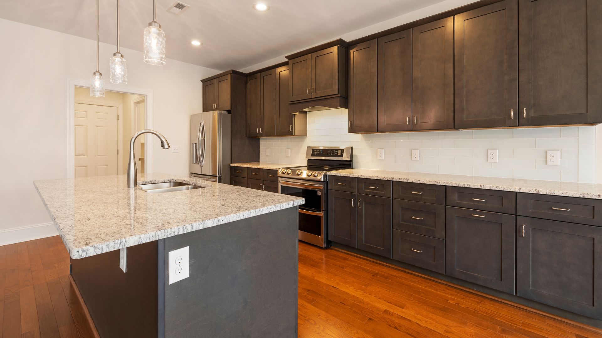 Dark brown Wall kitchen cabinets with white countertop and maple flooring