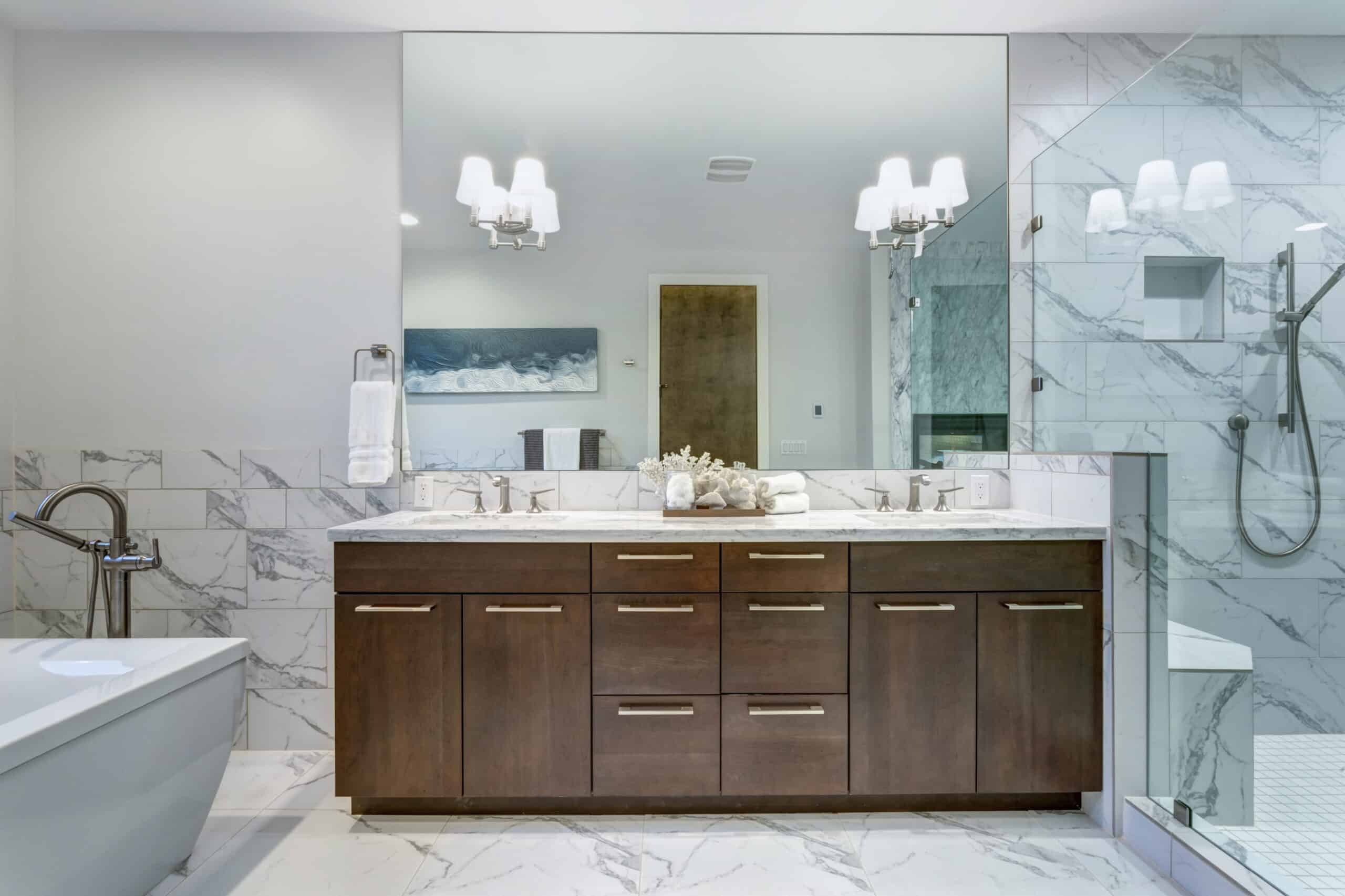 Incredible master bathroom with Carrara marble tile surround, modern glass walk in shower, espresso dual vanity cabinet and a freestanding bathtub.
