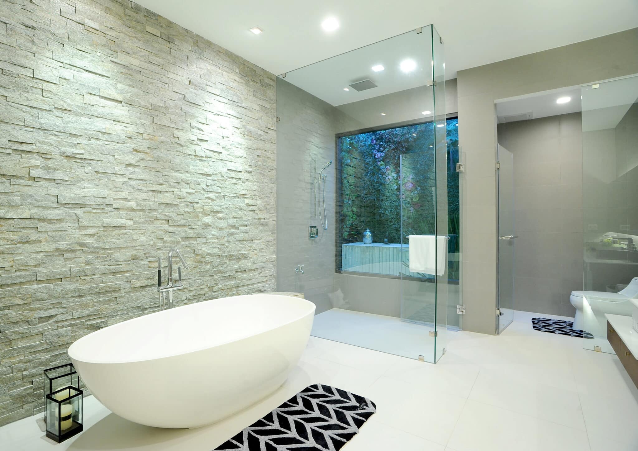 Luxury bathroom style with glass enclosed shower, a bath tub, and toilet
