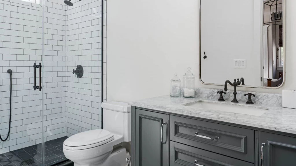 Small bathroom with toilet, shower, and grey bathroom cabinets with white countertop