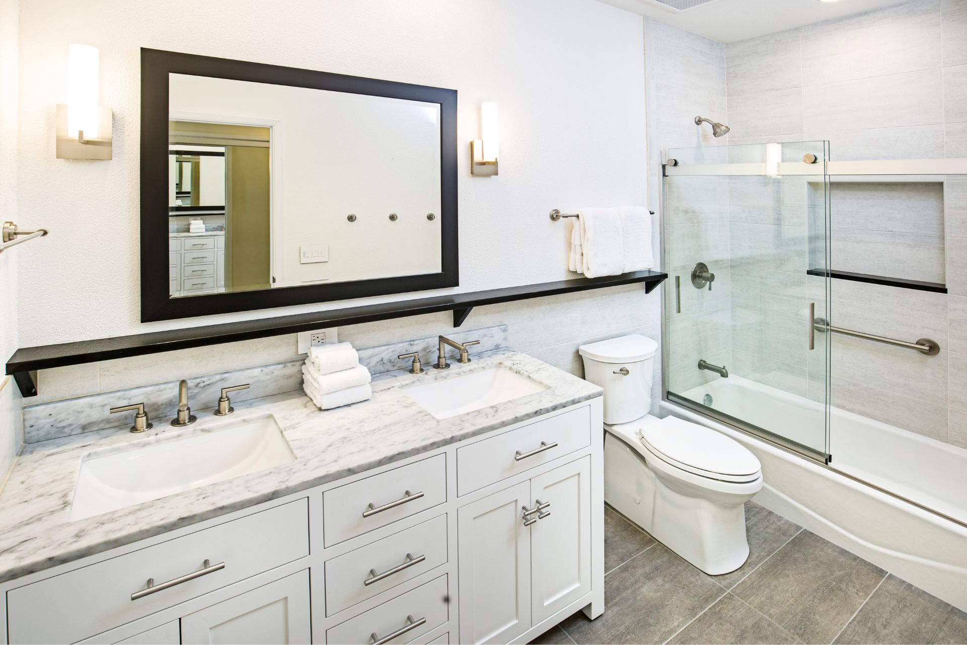 White bathroom with shaker double-sink vanity, toilet, and bath tub