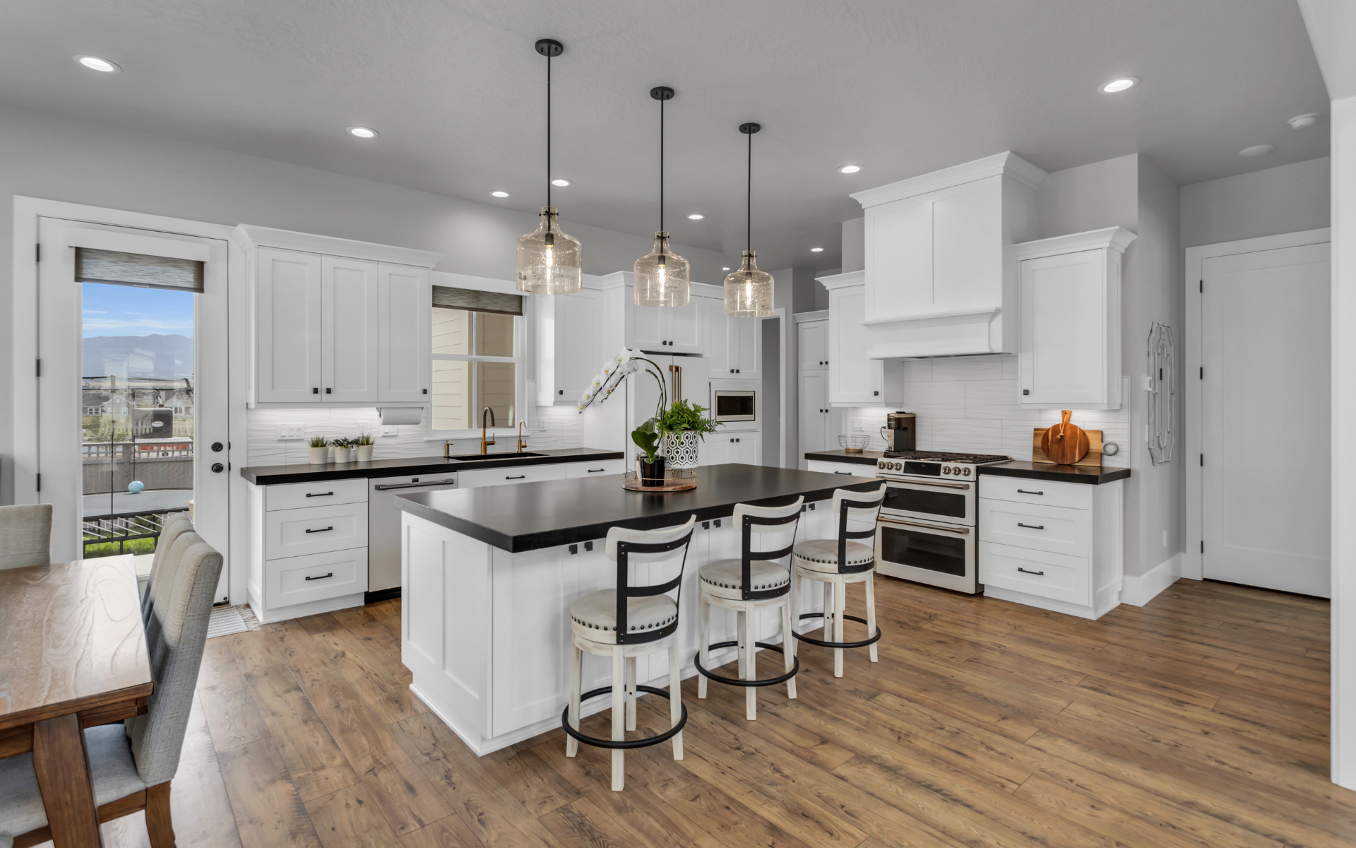 Elegant kitchen with white cabinets, black countertop, and wood flooring