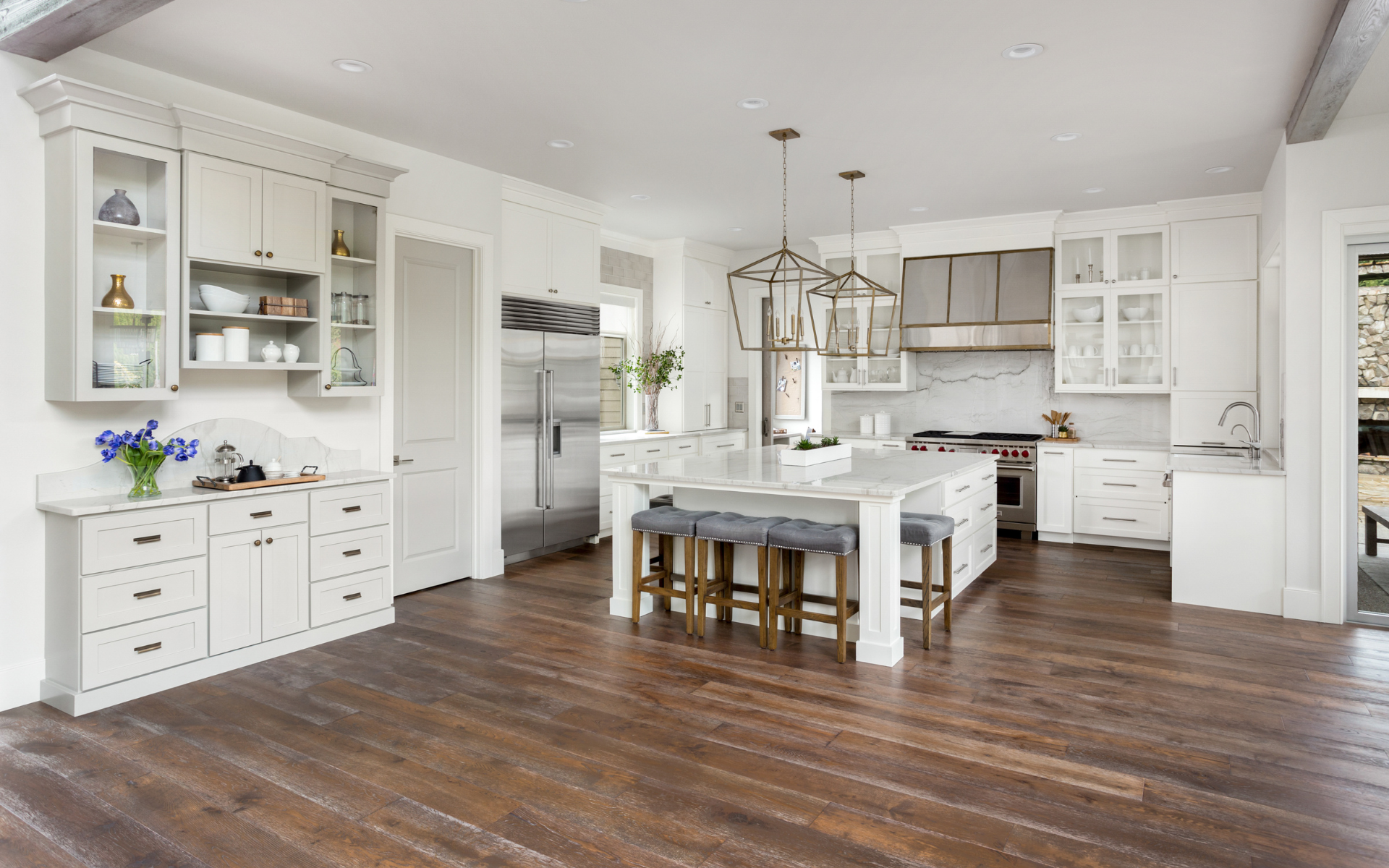 Spacious kitchen with white shaker cabinets and brown flooring