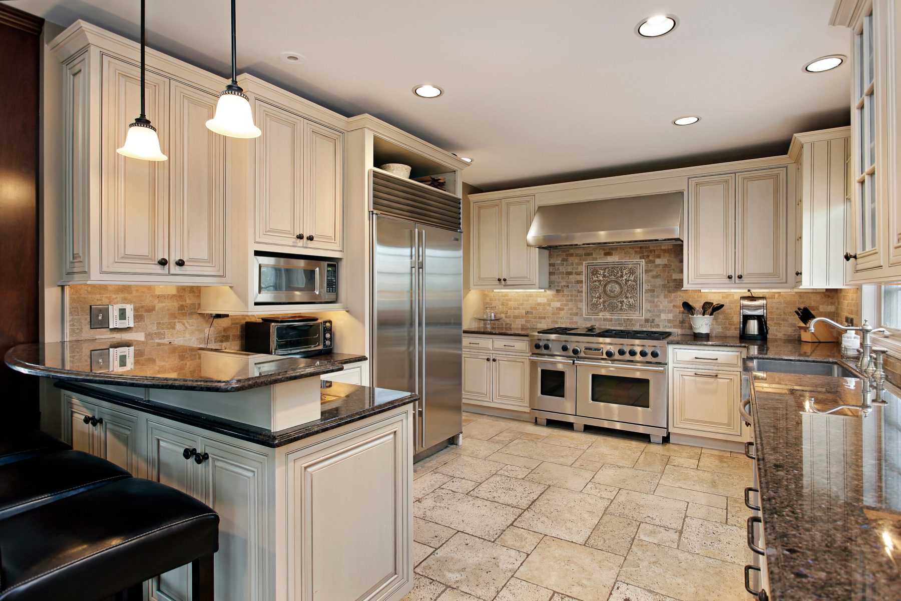 upscale luxury kitchen design with white cabinetry and black countertop