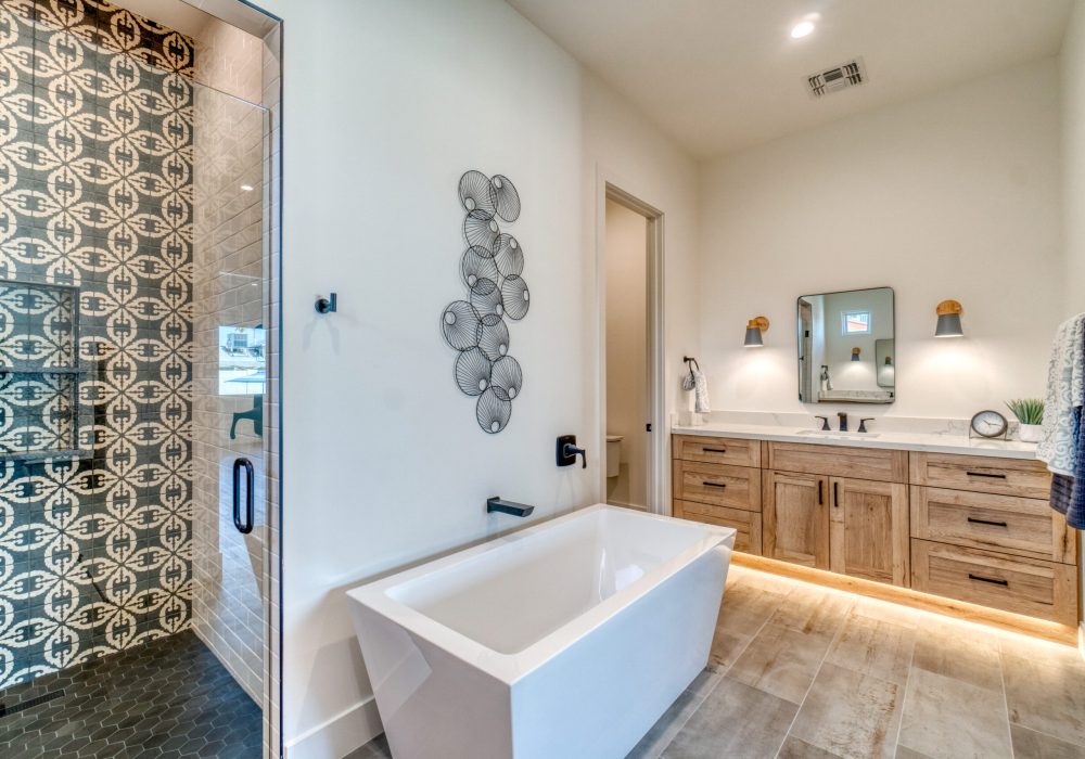 Traditional bathroom style with bath tub, brown single sink vanity, and a shower having glass tiles