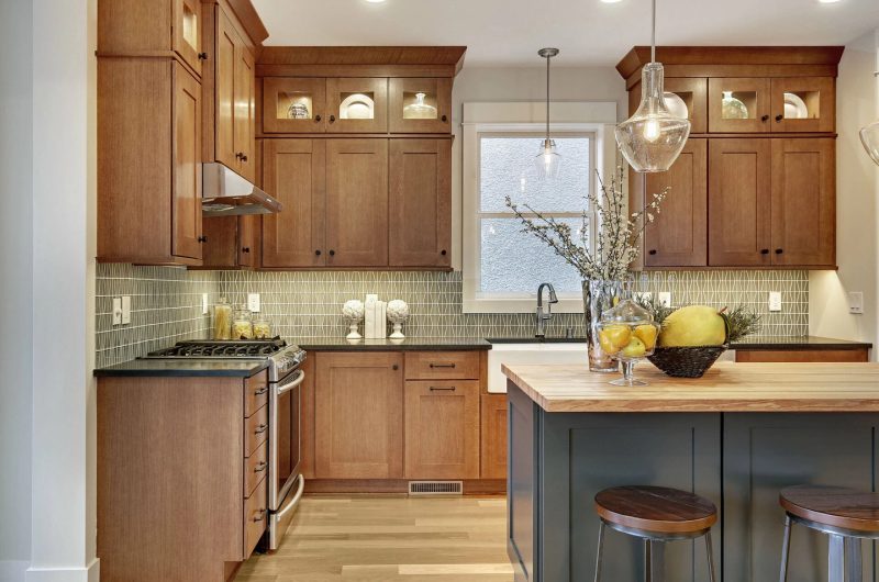 Brown kitchen design with black countertop and beige kitchen island top on blue cabinet